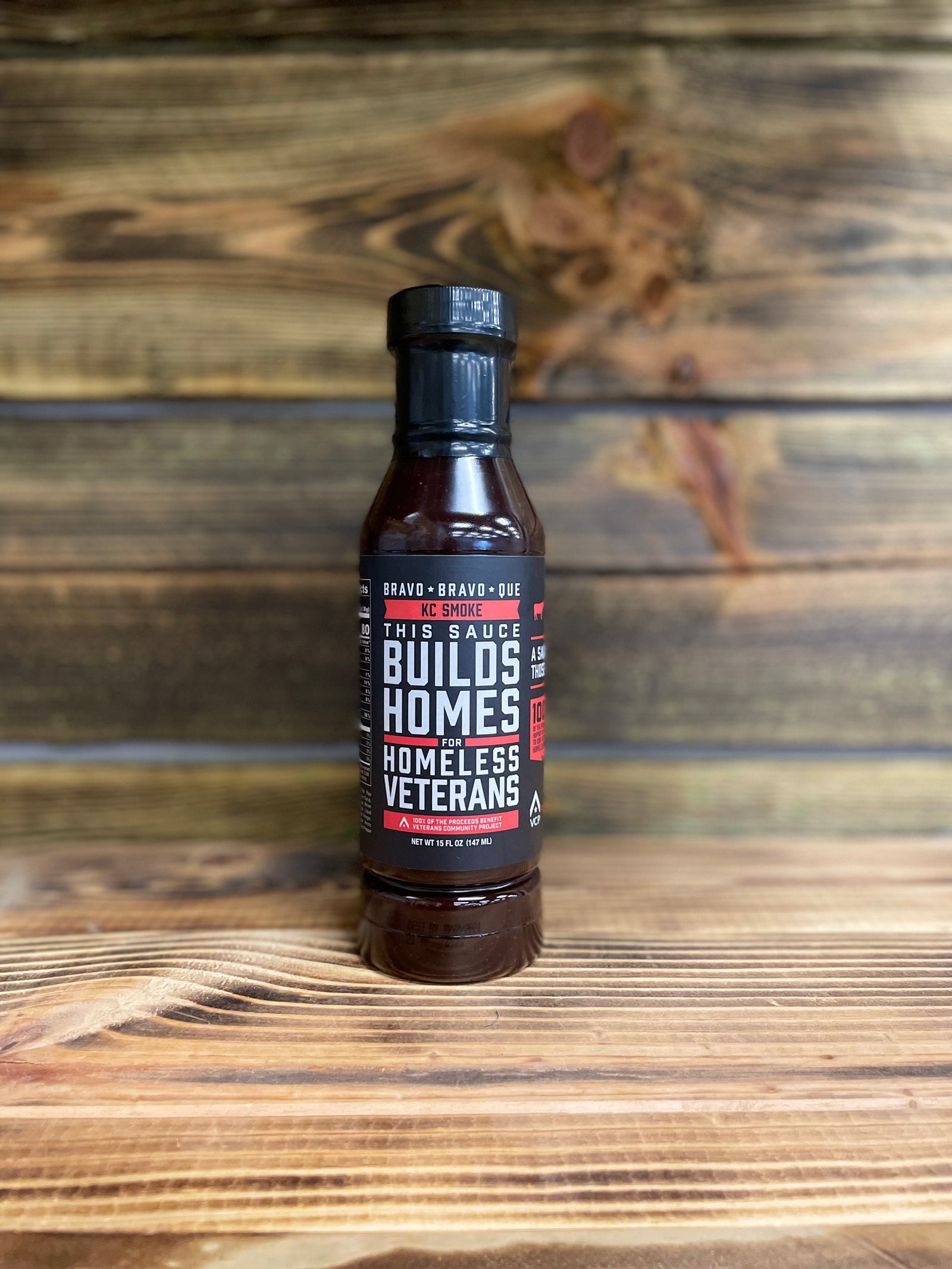 A bottle of KC Smoke barbecue sauce placed on a wooden surface.