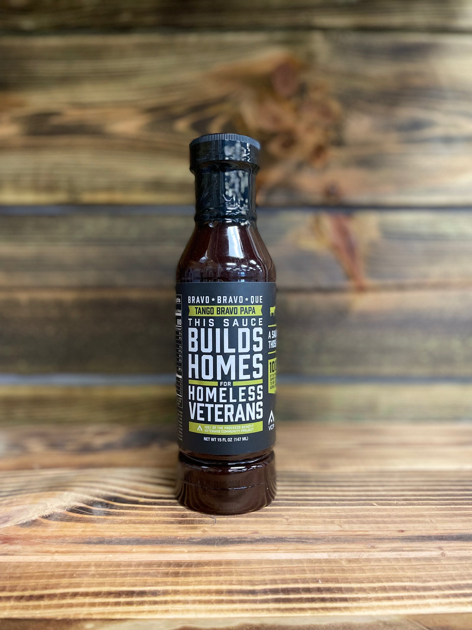 A bottle of Tango Bravo Papa barbecue sauce placed on a wooden surface.