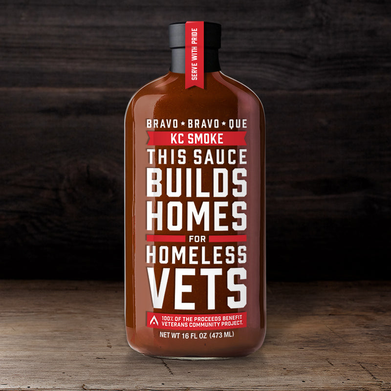 A bottle of Bravo Bravo Que KC Smoke barbeque sauce, with a label stating 'This sauce builds homes for homeless Vets'.